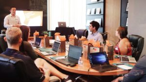 man standing in front of people sitting beside table with laptop computers